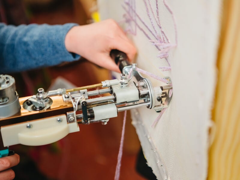 close-up of a hand holding a rug tufting gun