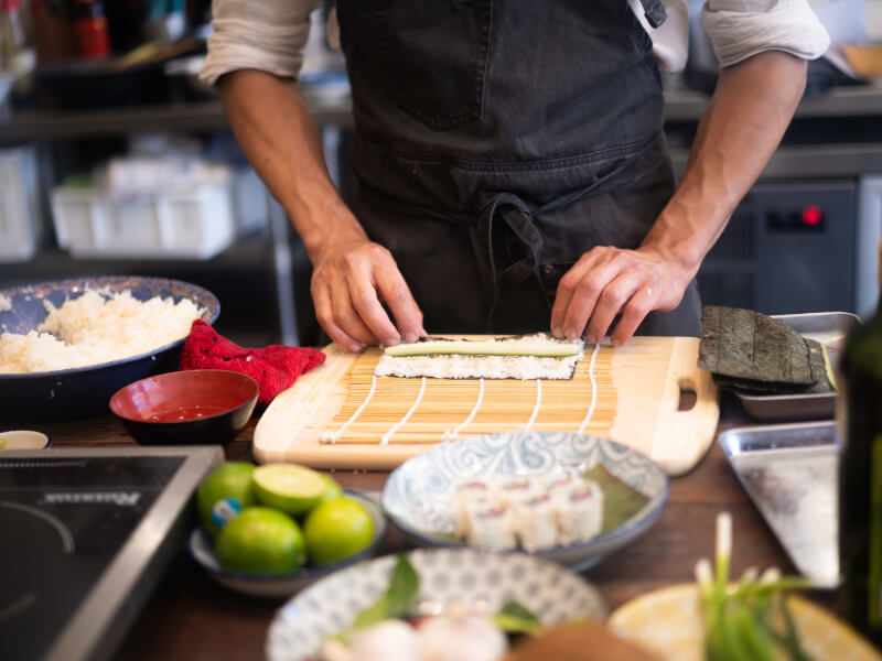 Close up of a man rolling sushi at an Asian cooking class