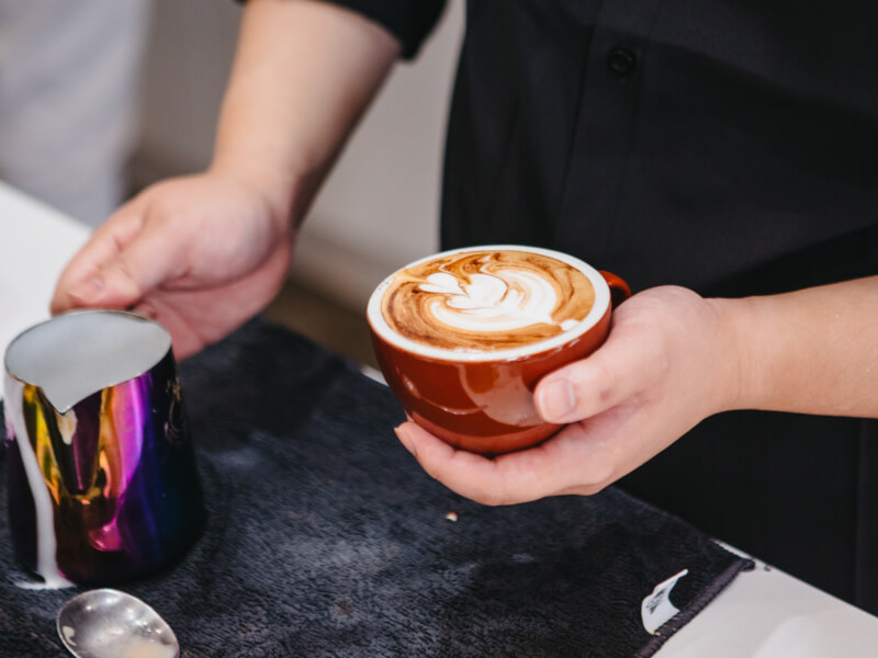 Man holding a cup of coffee after pouring milk