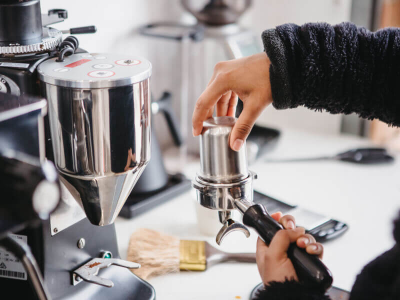 A student tamps coffee at a barista course