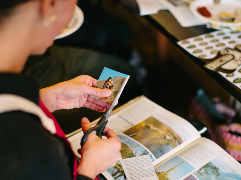 A woman cuts out magazines at her collage class