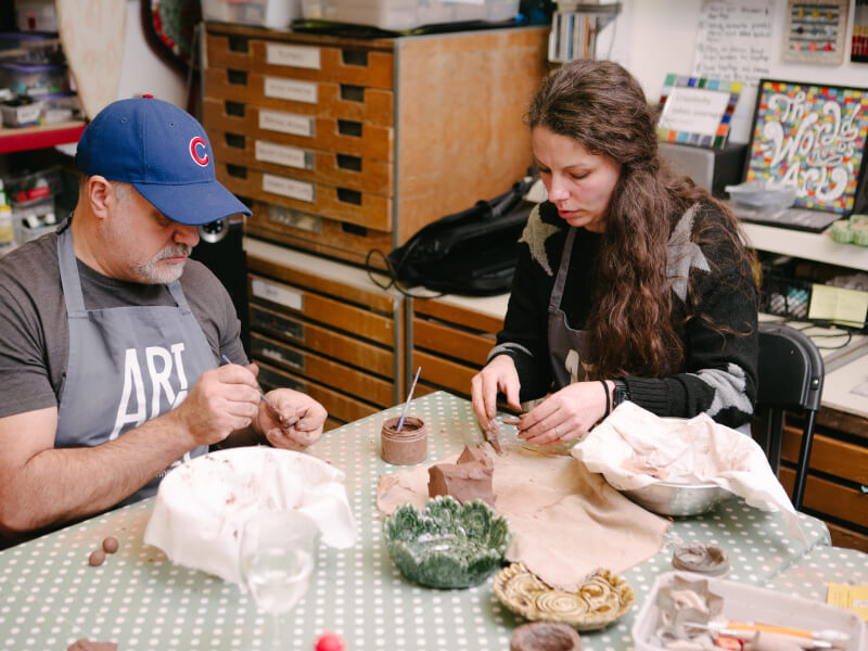 Two colleagues at a pottery class making ceramic bowls
