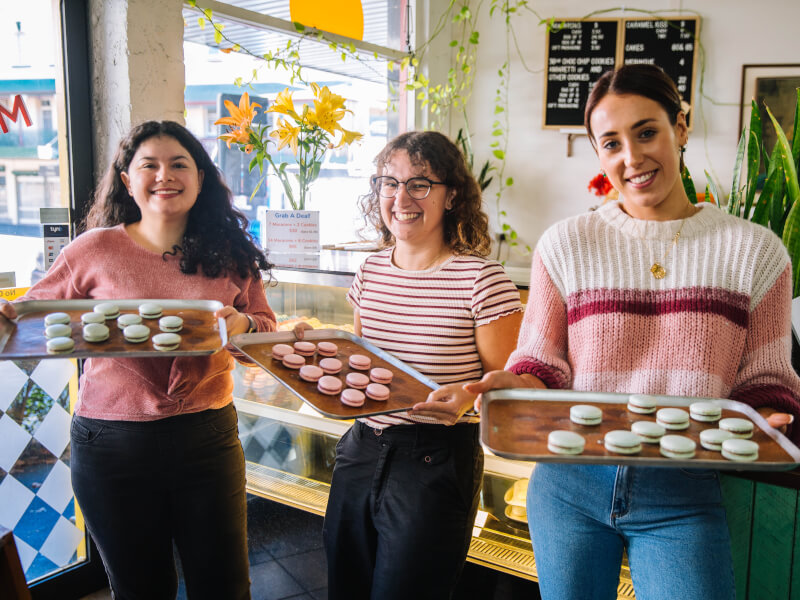 Colleagues smiling with trays of macaroons at a baking class for team building
