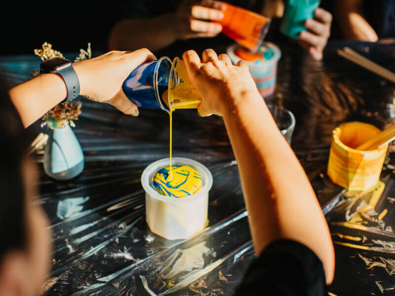 An adult mixing and pouring colourful paints