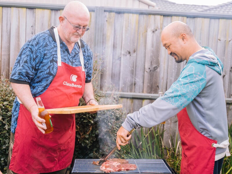 Two men cooking meat on a barbecue