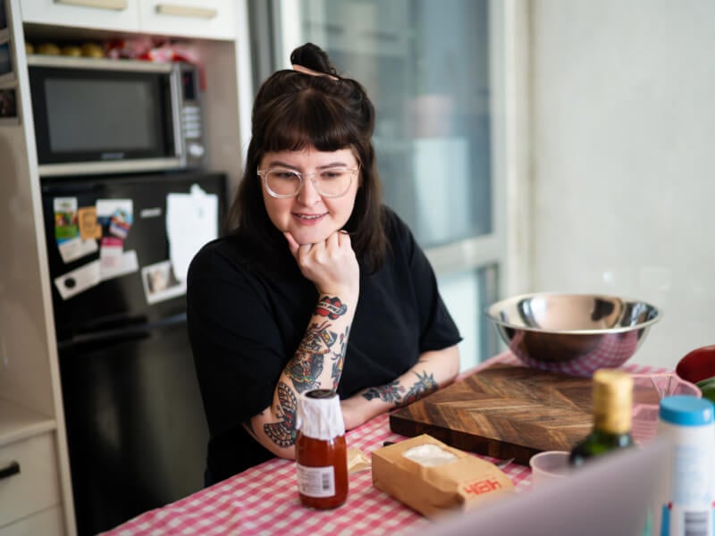 A woman cooks pizza while following an online cooking class