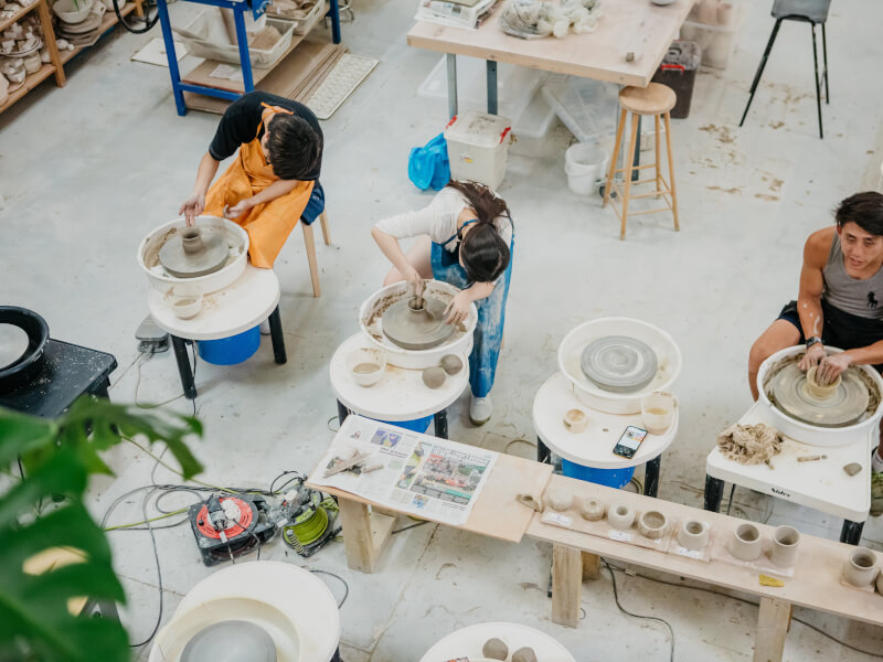Colleagues wheel throwing at pottery class for team building