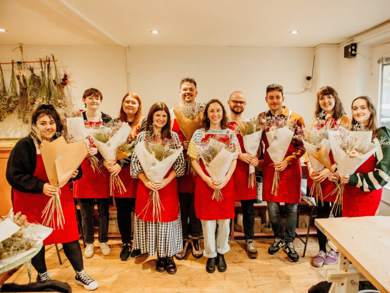 A corporate group posing with their flower arrangements