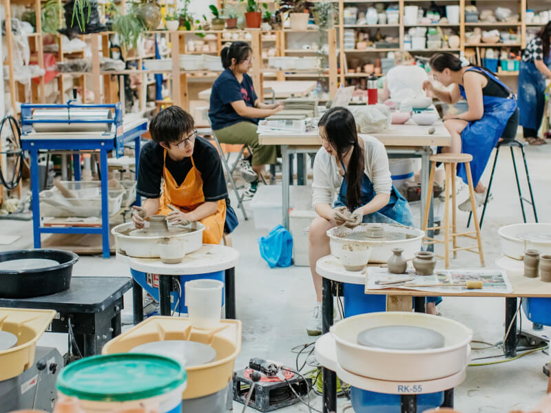 A couple enjoy a pottery class as a gift for him
