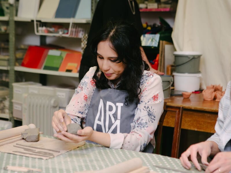 A woman focuses on moulding clay at a pottery class