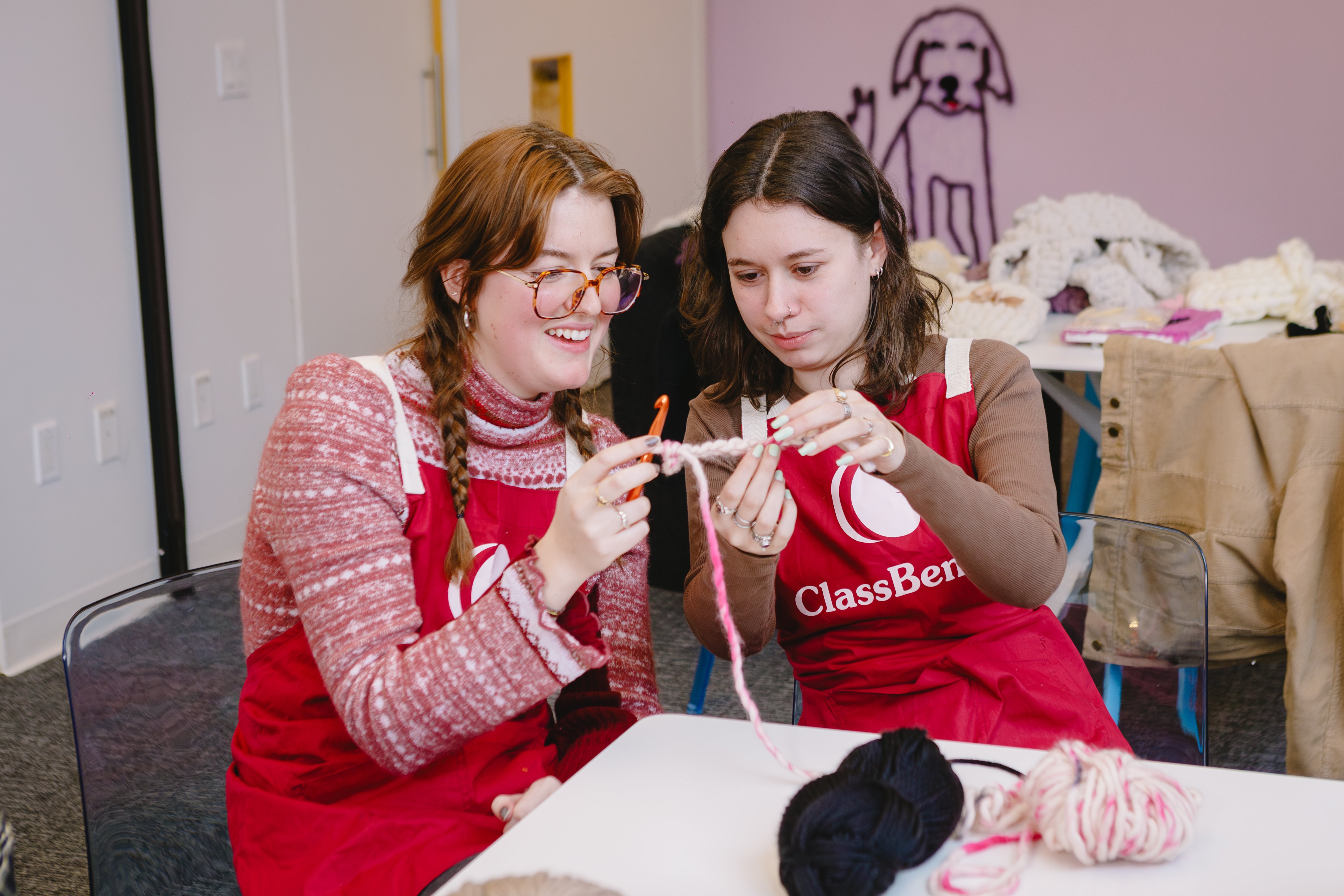 Two friends learning crochet together and smiling