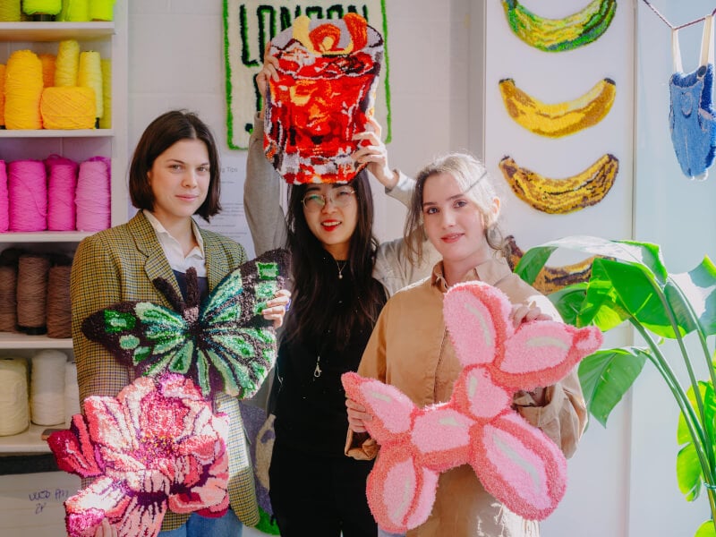Friends pose with their tufted rugs