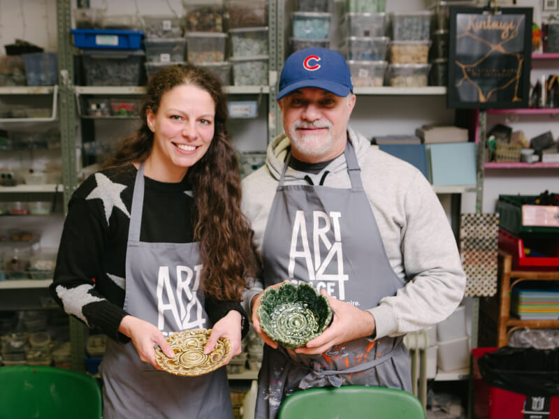 A father and daughter proudly show off their handmade pottery