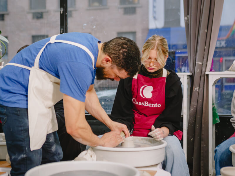 A father helps his daughter with pottery