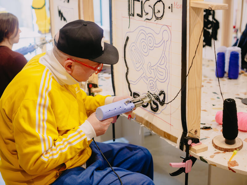 A father makes a rug with a tufting gun
