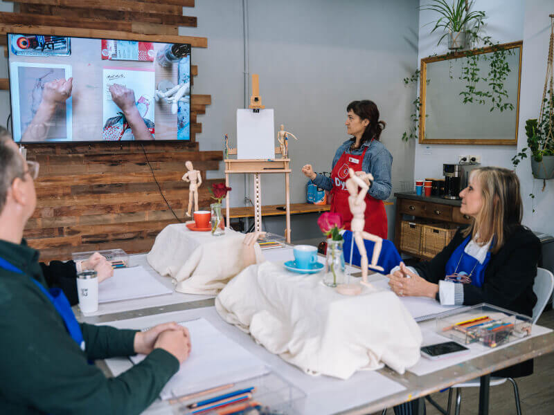 A group of drawing students watch a drawing demonstration