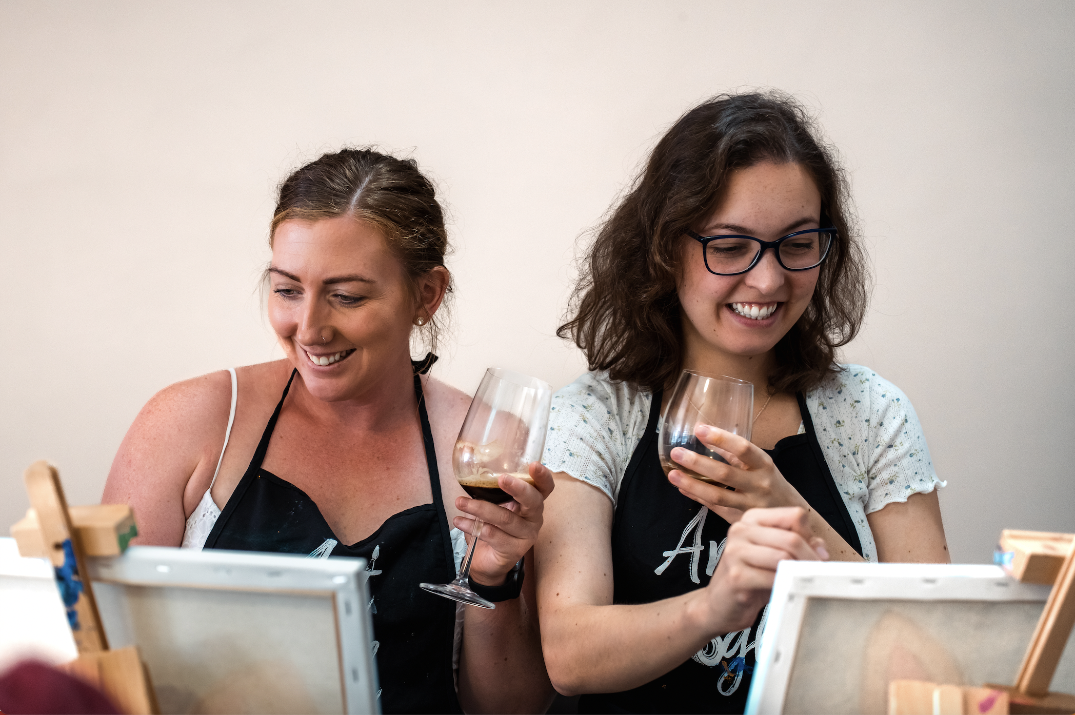 Women holding their wine glasses while painting
