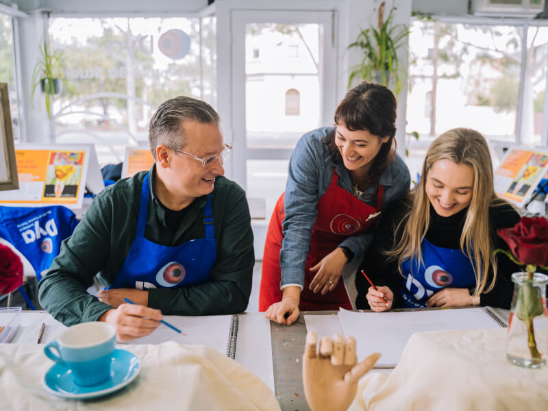 A man and his daughter bond at a drawing class