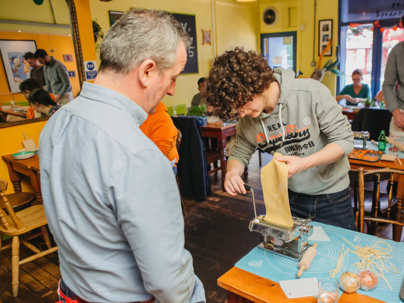 Father and son making pasta from scratch at a family-friendly pasta making class