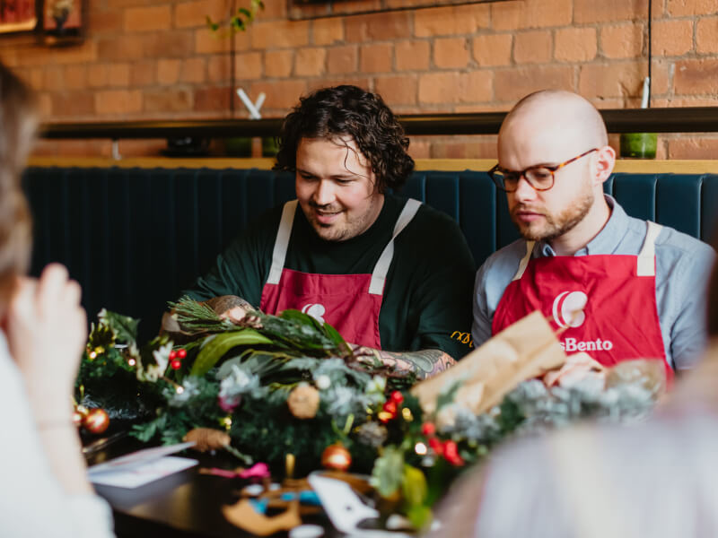 Two colleagues make Christmas wreaths at their work party