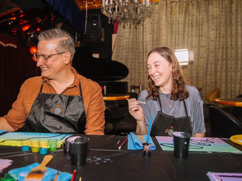 Man and woman laughing whilst painting.