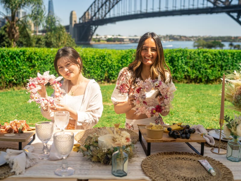 Two women are smiling while they hold up their finished flower crowns