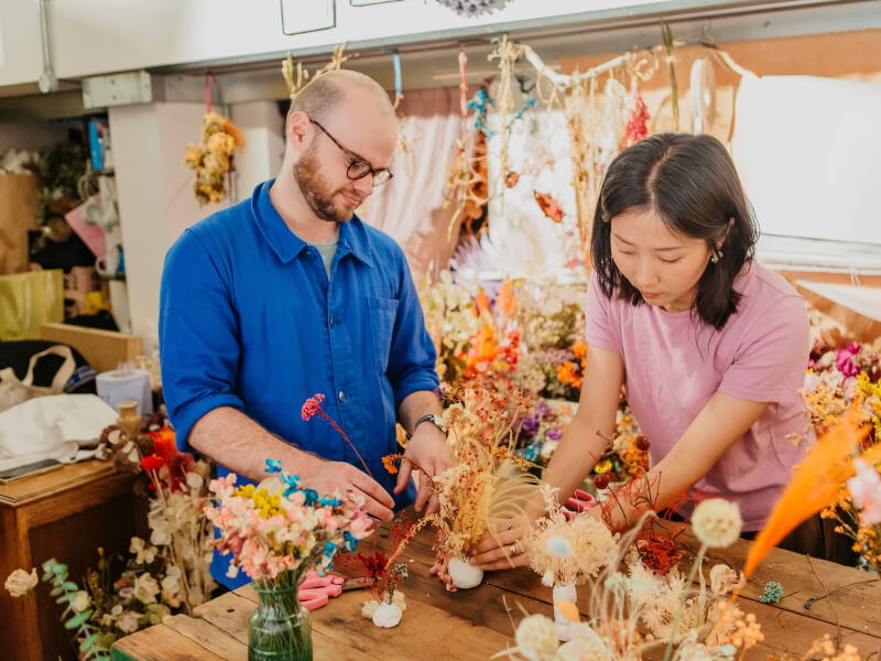 Man and woman flower arranging in a florists studio surrounded by flowers