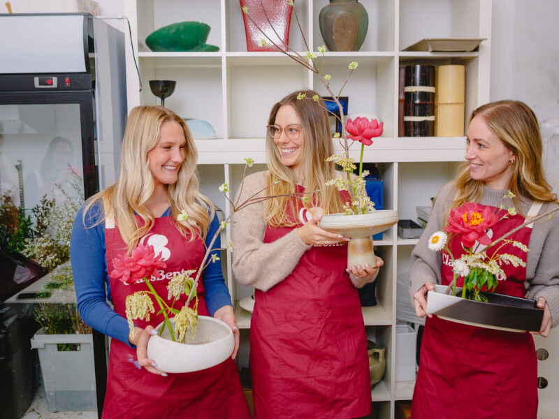 Three women happily pose with their flower arrangements