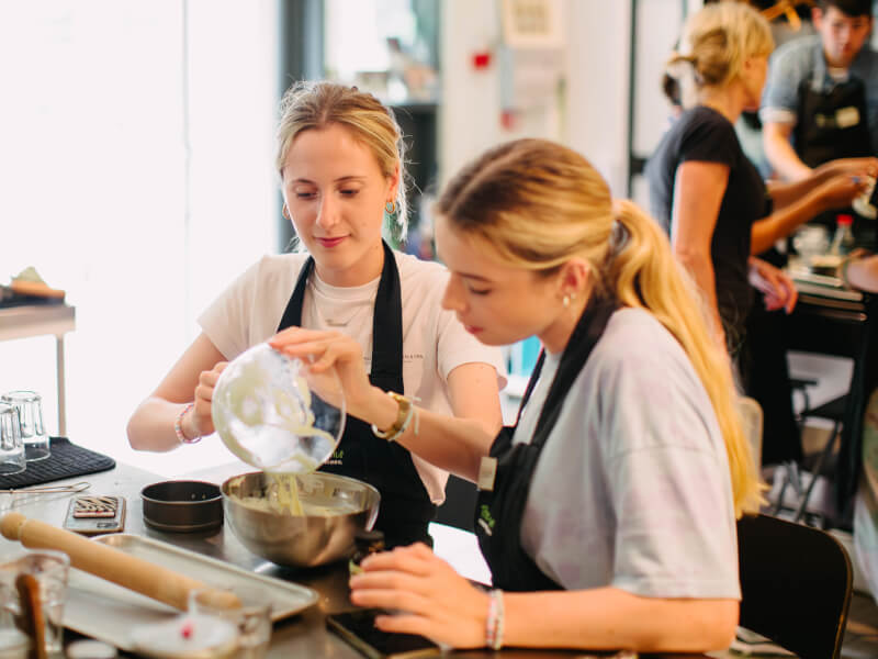 Two women cooking together at a class