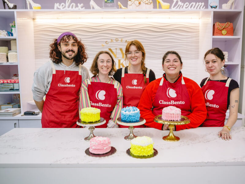 A group of friends in ClassBento aprons pose with their decorated cakes