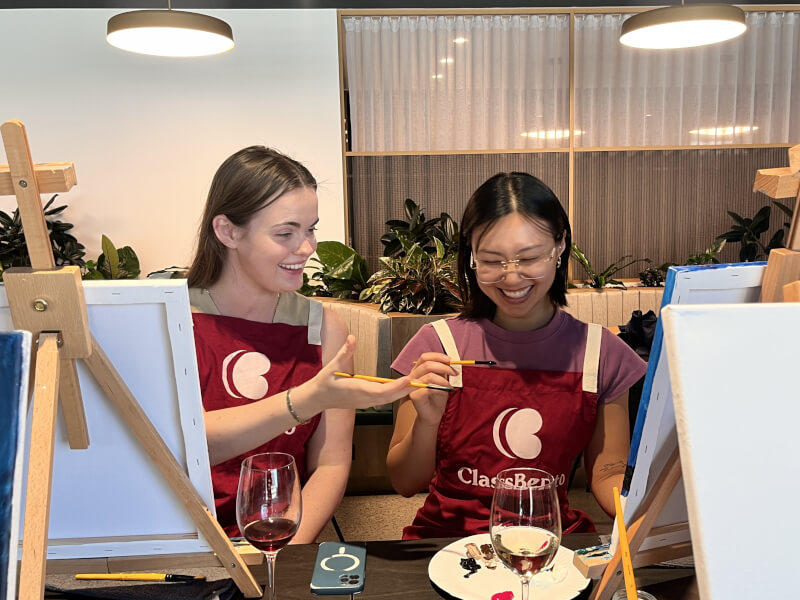 Two friends smiling and laughing at a paint and sip