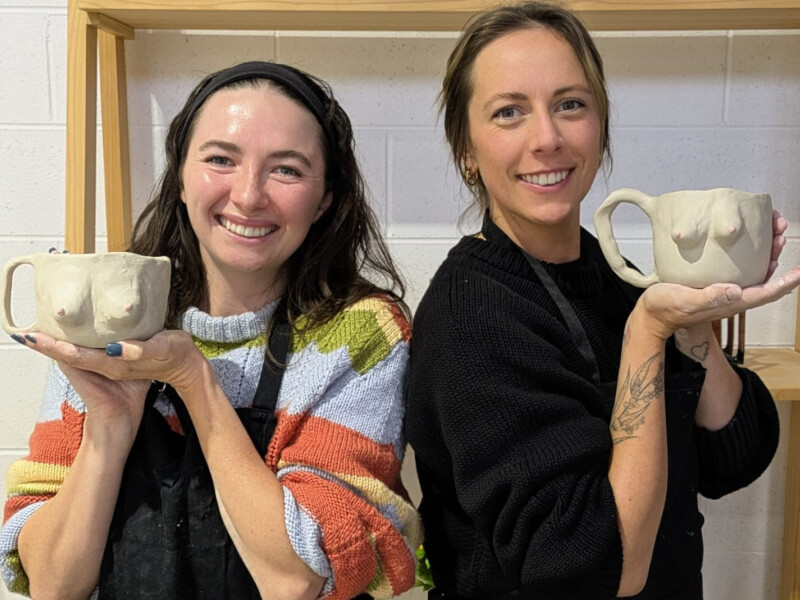 Two friends hold their handmade boobie mugs