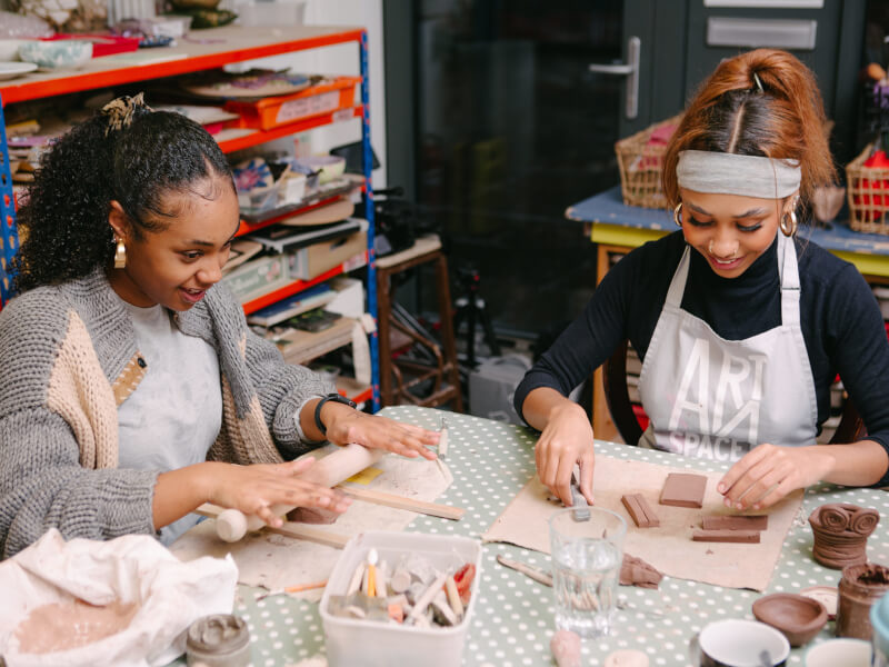 Friends smile as they make pottery at a pottery class