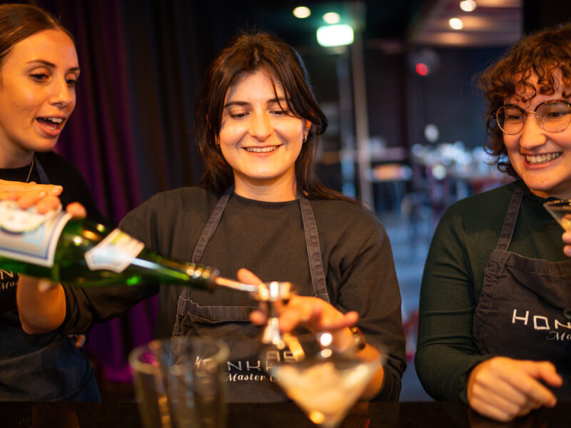 A trio of friends making cocktails at a mixology birthday experience