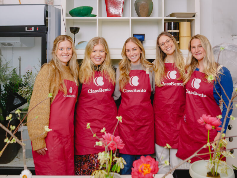 A group of girlfriends stand behind their flower arrangements