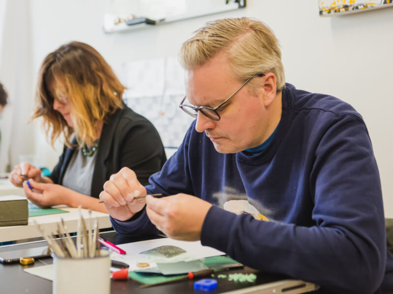 A man concentrating whilst making jewellery at a craft class.
