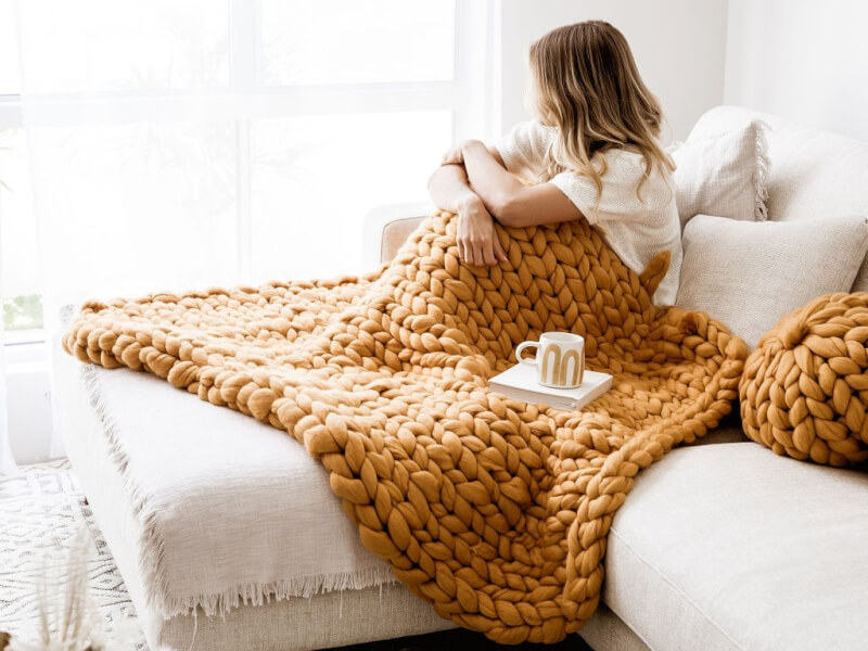 Woman relaxing on the couch with giant knitted throw
