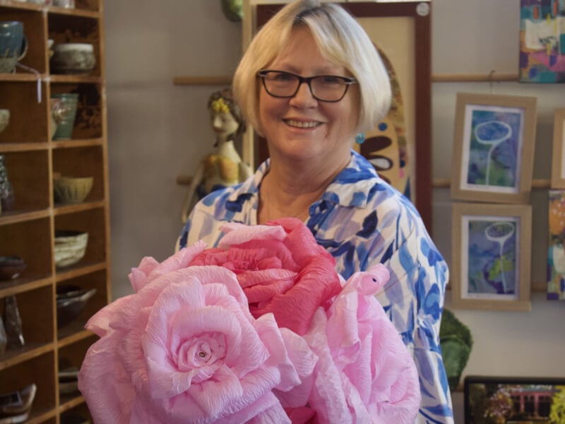 A woman holding a giant paper flower bouquet