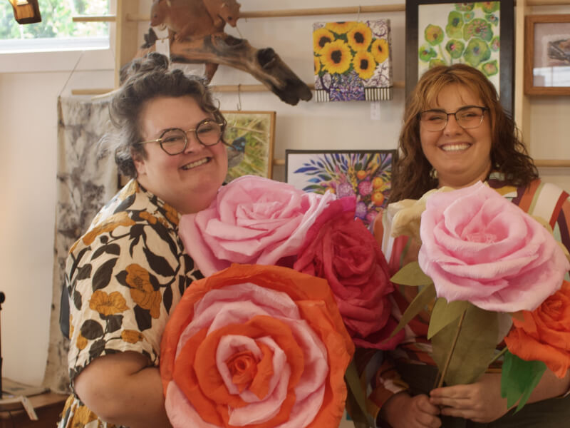Two friends showing off their giant paper flowers