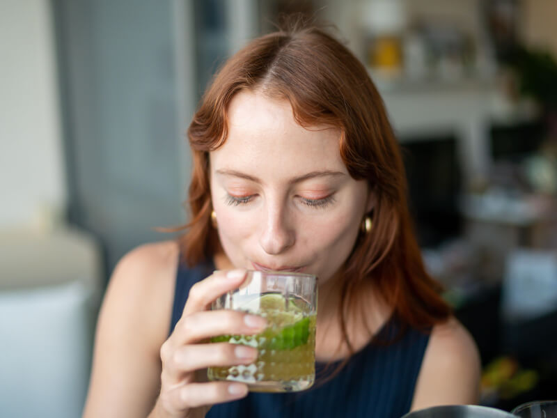 A woman sipping on a cocktail she made