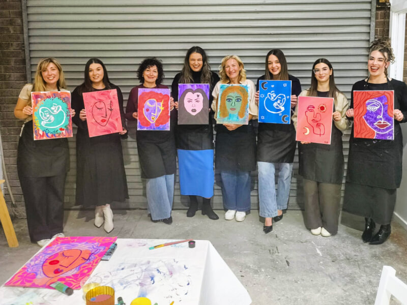 A group of women holding their paintings of each other