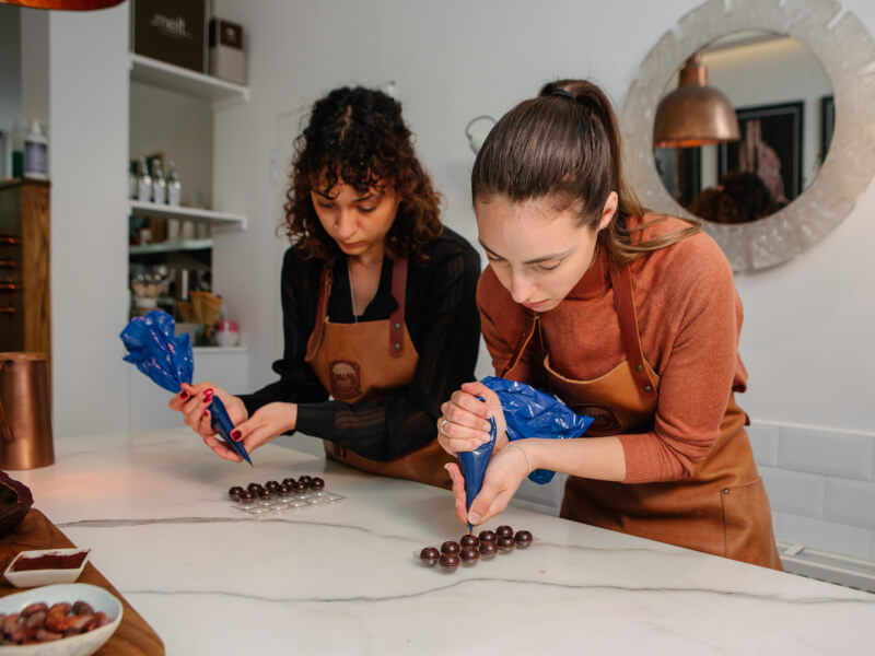 Two women make chocolate truffles