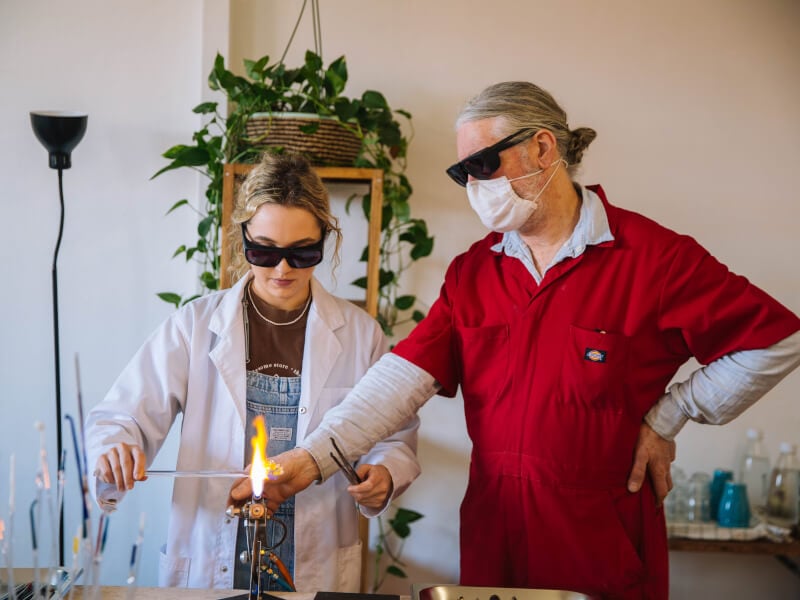 A woman and a man learning glassblowing