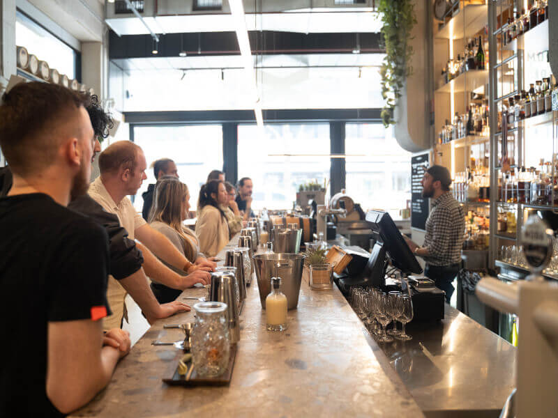 A group of coworkers watching a cocktail making demo