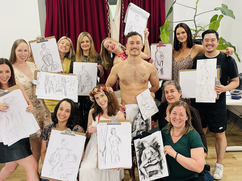 A group poses with their life drawings and their male model