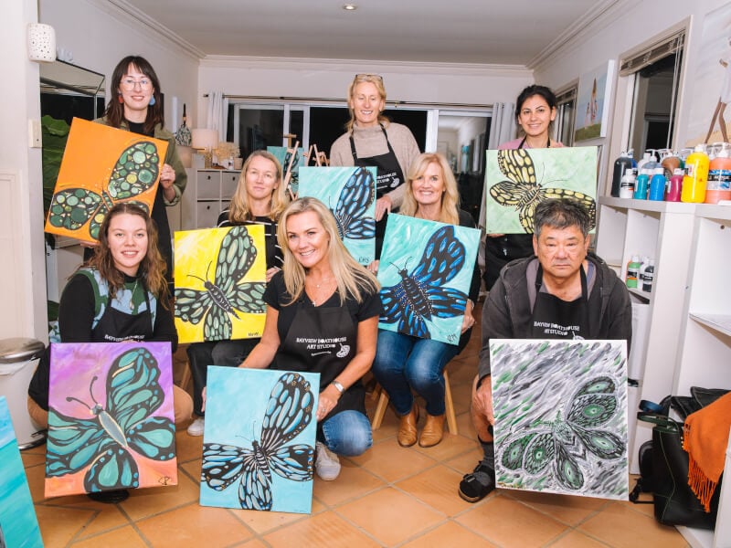 Happy team members pose with their paintings