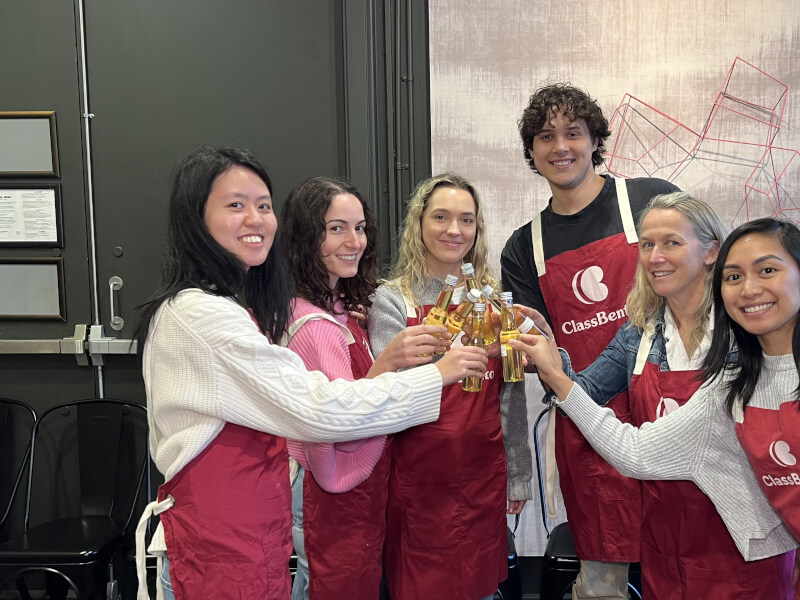 Team smiling and clinking limoncello bottles together