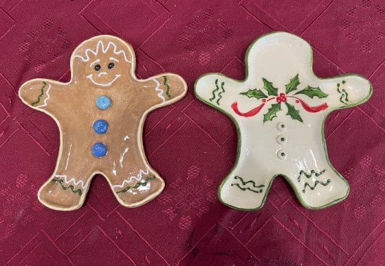 Two ceramic gingerbread men on maroon-coloured tablecloth