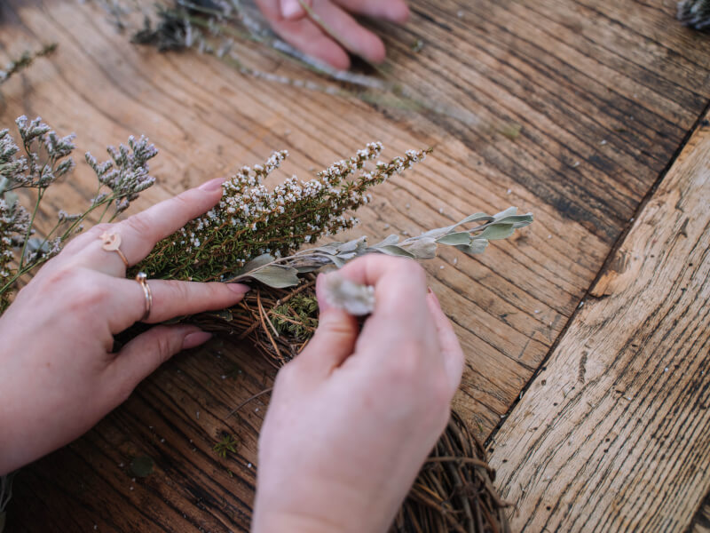 Hands making a dried flower Christmas wreath
