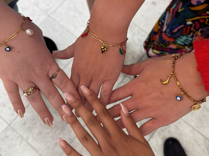Three hands showing off their charm bracelets
